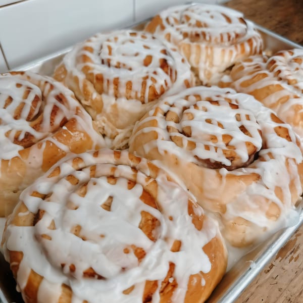 A tray of freshly baked cinnamon rolls with white icing drizzled on top at Brewed Awakening.