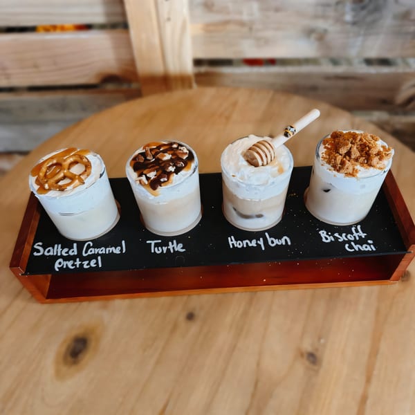 Four iced coffee drinks with various toppings, including pretzel, nuts, honey dipper, and cookie crumbles.