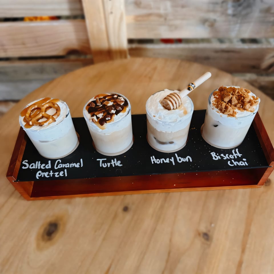 Four iced coffee drinks with various toppings, including pretzel, nuts, honey dipper, and cookie crumbles.